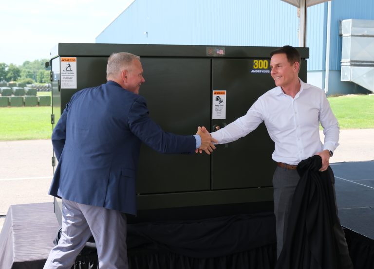 Ermco President and CEO Tim Mills shaking hands with David O’Brien, Exelon Senior Vice President and Chief Supply Officer in front of the 9 millionth transformer, with the transformer prominently displayed in a celebratory setting.