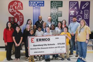 Group of ERMCO representatives, students, and Dyersburg City Schools staff displaying a ceremonial $75,000 STEM initiatives donation check in front of a colorful STEM?themed wall.